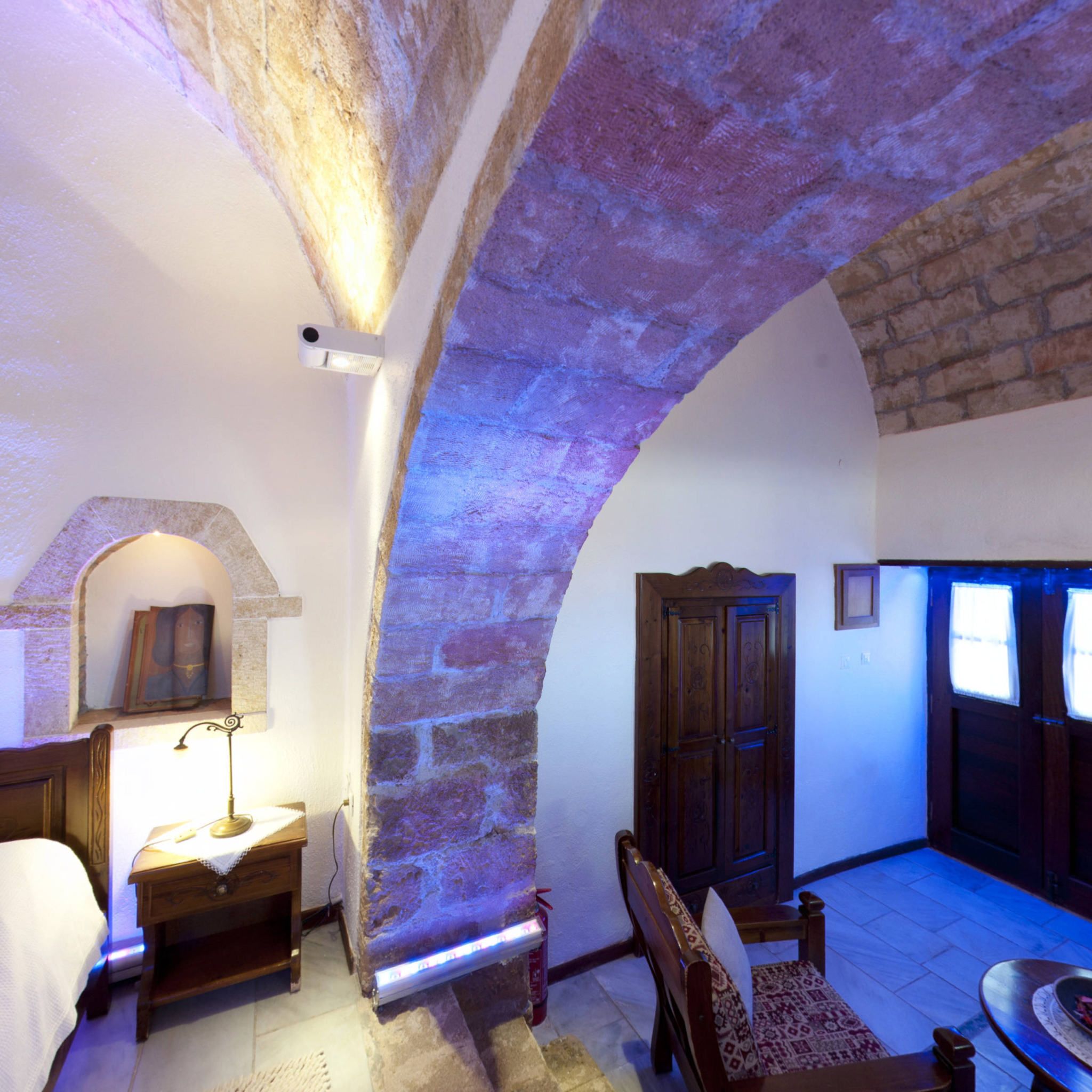 Una habitación acogedora con un arco de piedra, una puerta de madera, una mesita y una silla.