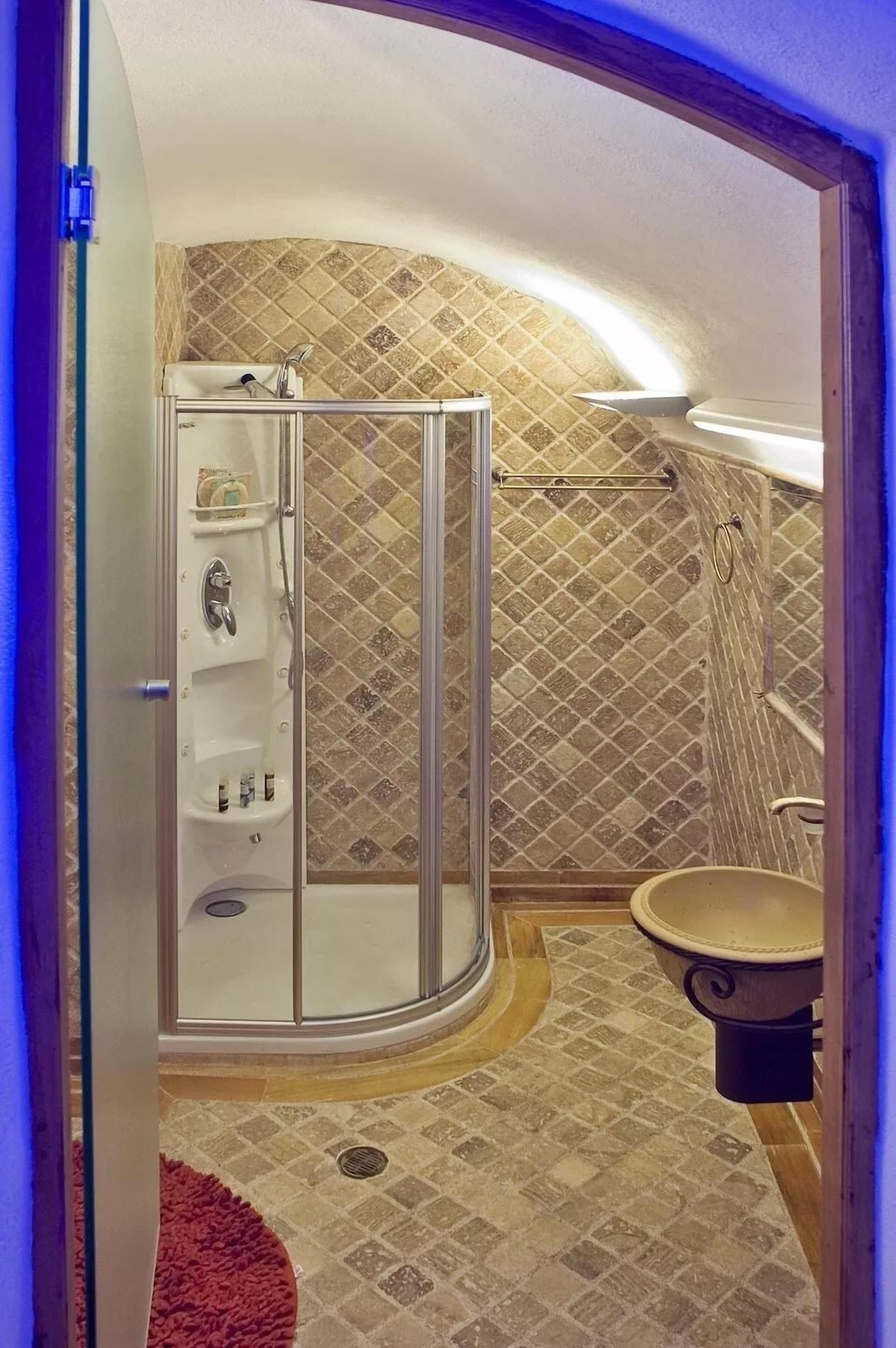 A bathroom with a glass-enclosed shower, a sink, and a toilet.