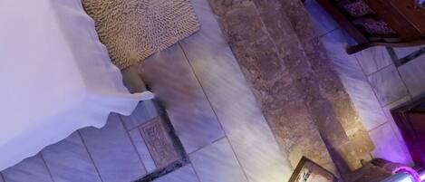 A room with a patterned rug, a white bedspread, a tiled floor, and wooden furniture.