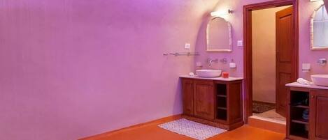 A bathroom with a purple wall, wooden cabinets, a sink, and a mirror.