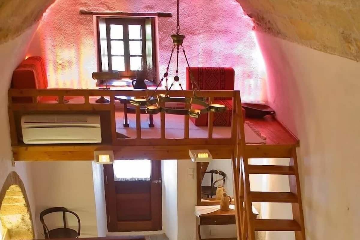 A cozy, multi-level interior with a vaulted ceiling, wooden furniture, and a staircase.
