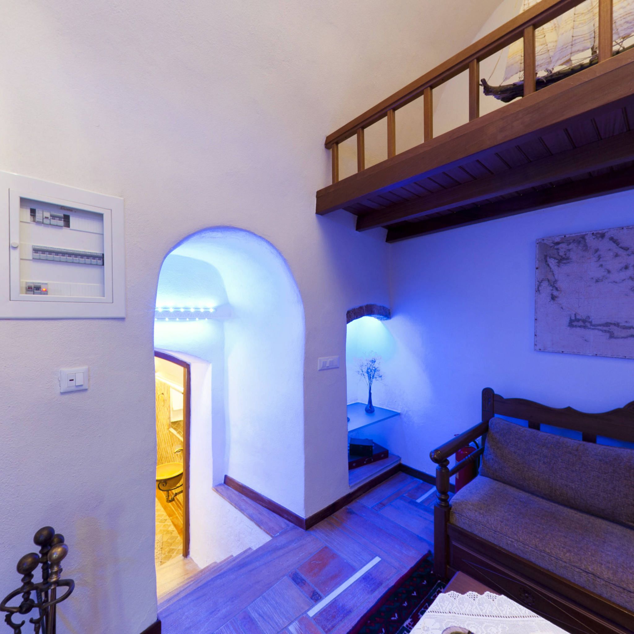 A room with a wooden bench, a small table with a vase, and a wall-mounted light fixture.
