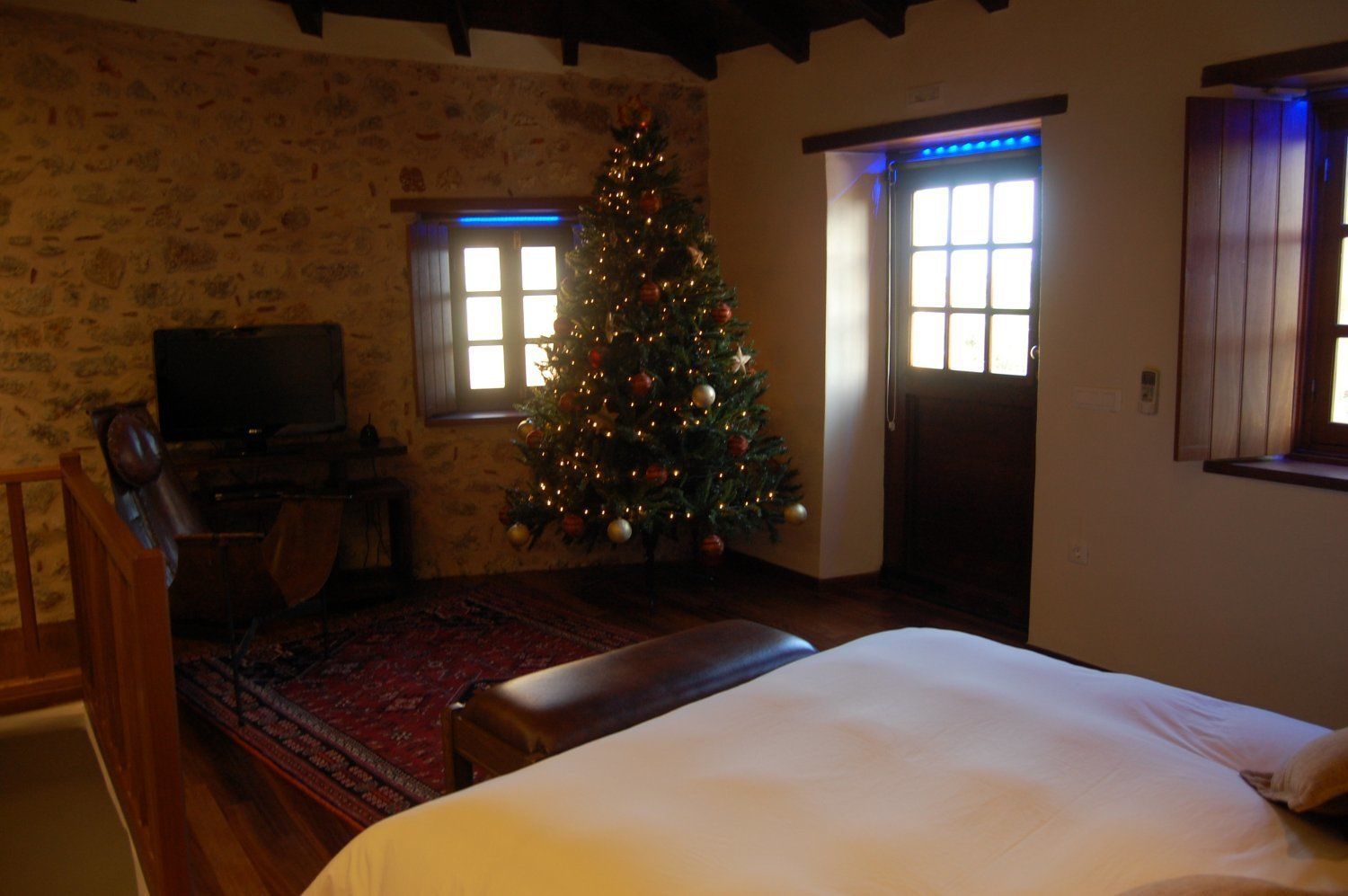 Una habitación acogedora con una cama, un televisor, un árbol de Navidad y una chimenea.