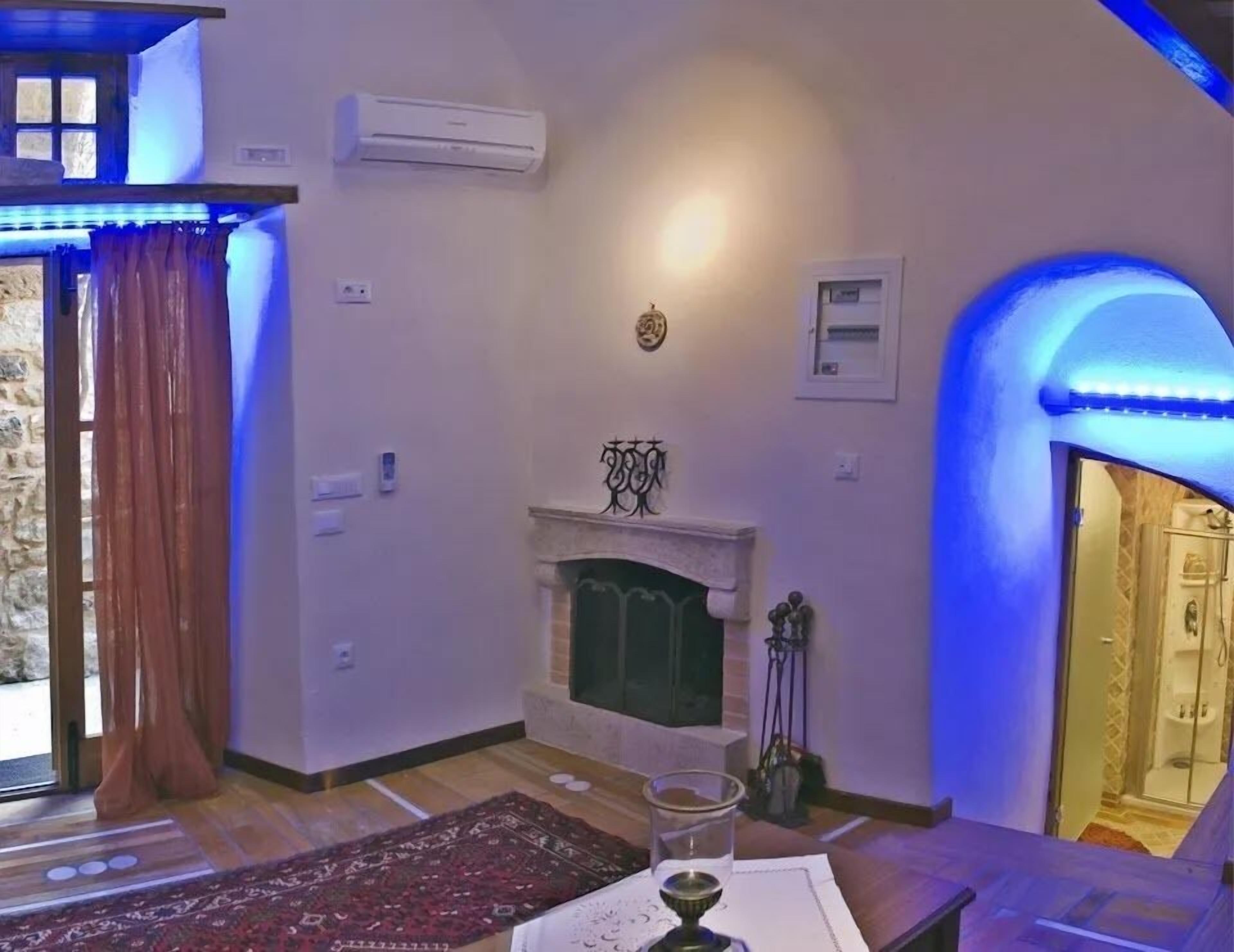 Una habitación acogedora con chimenea, una pared de piedra y un arco iluminado en azul.