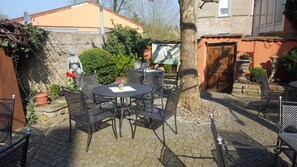 An outdoor patio with a round table and chairs, surrounded by stone walls and vegetation. - Gasthaus Krone (Wiesentheid)