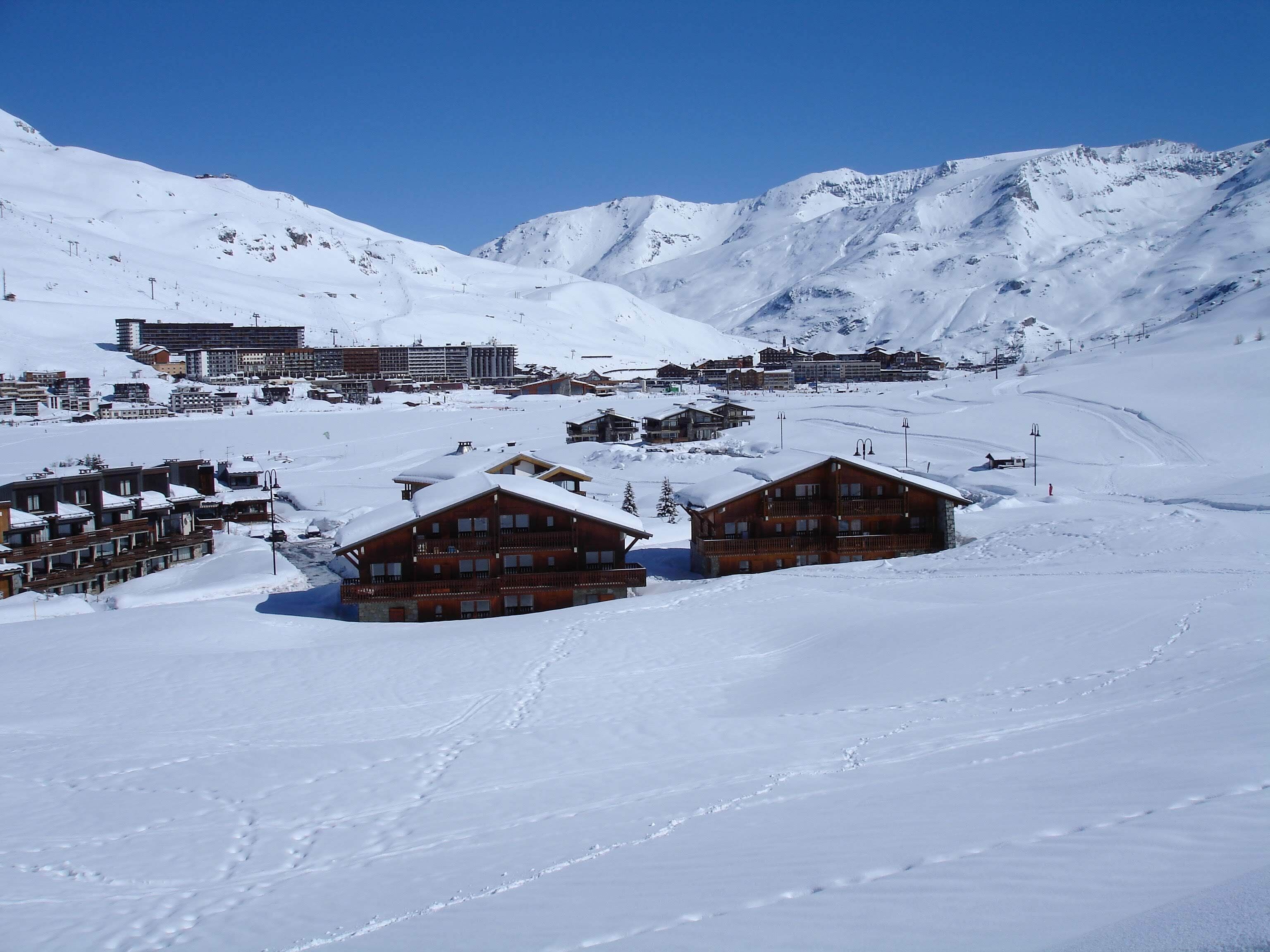 Un paysage montagneux enneigé, avec des chalets en bois et une station de ski en arrière-plan.