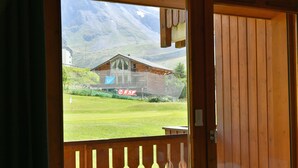 A wooden door with a view of a mountain and a building with a sign reading "ESF". - Grand Cap 4 - Appt 4 pers in Chalet - CALM & NATURE (Tignes)