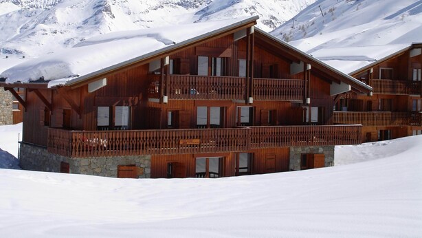 A wooden chalet with multiple balconies, set against a snowy mountain backdrop. - Grand Cap 4 - Appt 4 pers in Chalet - CALM & NATURE (Tignes)