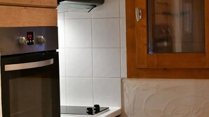 A kitchen with wooden cabinets, a stainless steel oven, a microwave, and a glass-fronted cabinet. - CHALET LE GRAND CAP 7 (Tignes)