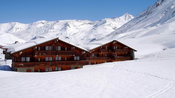 A wooden chalet with balconies, set against a snowy mountain backdrop. - CHALET LE GRAND CAP 7 (Tignes)