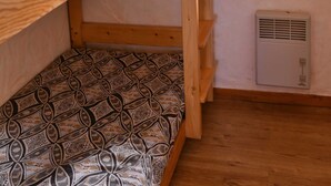 A bunk bed with patterned bedding, a window with a view of greenery, and a wall-mounted air conditioner. - CHALET LE GRAND CAP 7 (Tignes)