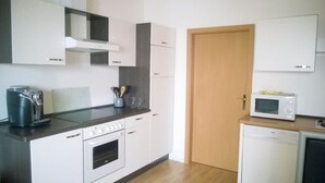 A compact kitchen with a built-in oven, a microwave, and a coffee maker. - Ferienwohnungen Peitz (Peitz)