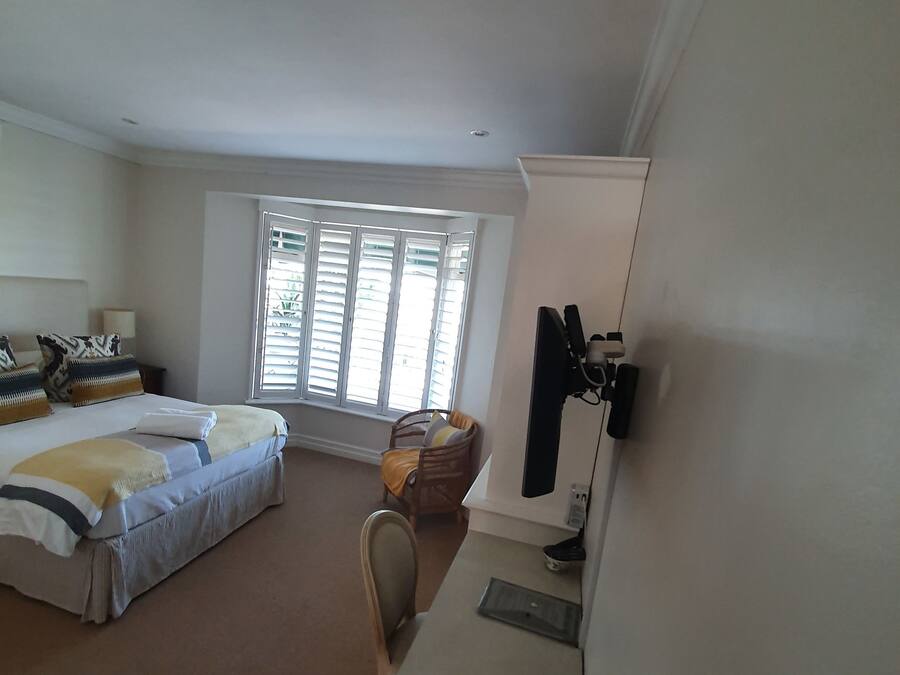 A hotel room with a bed, a desk, a chair, and a window with blinds.
