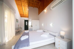 A bedroom with a bed, bedside table, and a desk with a chair. - Xi Village (Kefalonia)