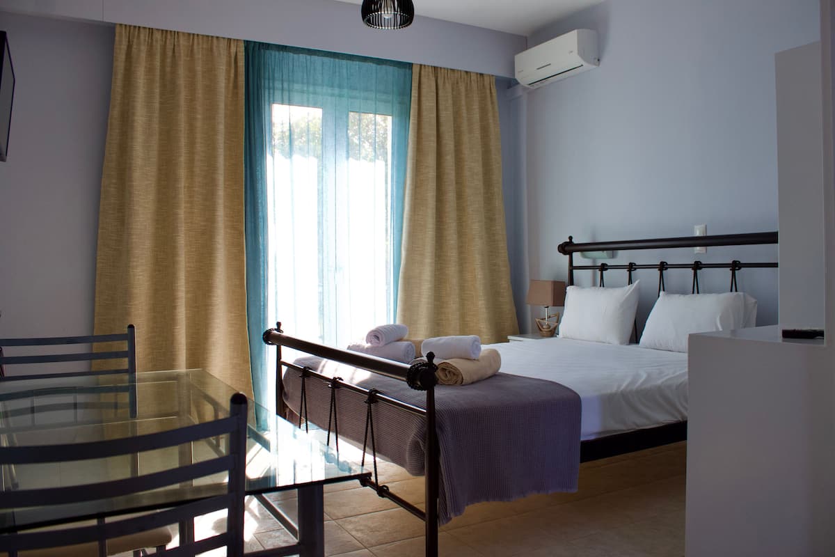 A hotel room with a bed, a glass table, and curtains.