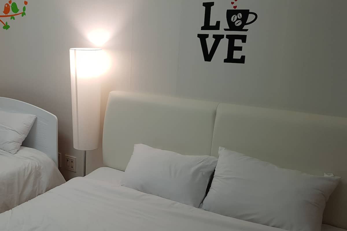 A hotel room with two beds, a small table, and a wall decoration.