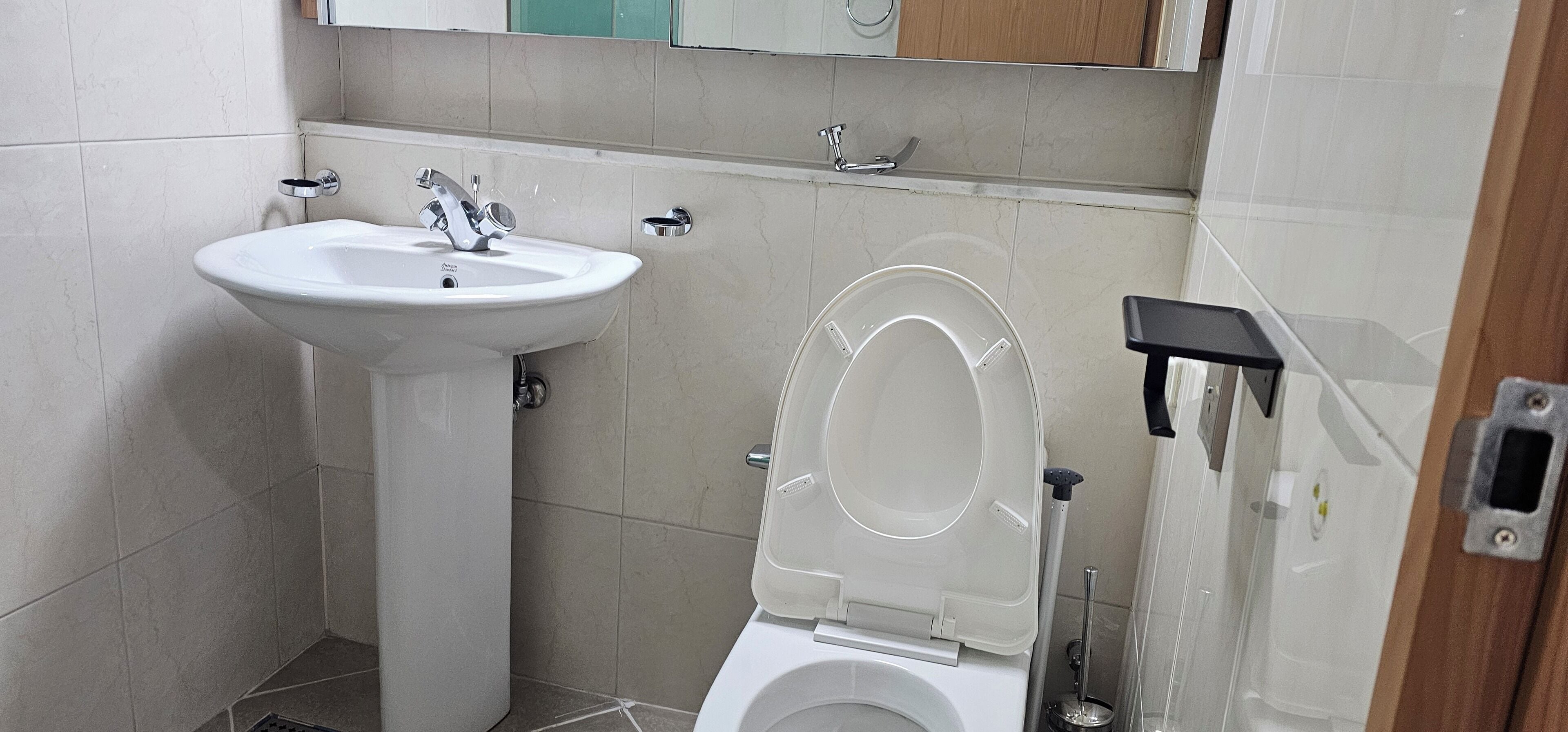 A small bathroom with a white sink, toilet, and a mirror above the sink.