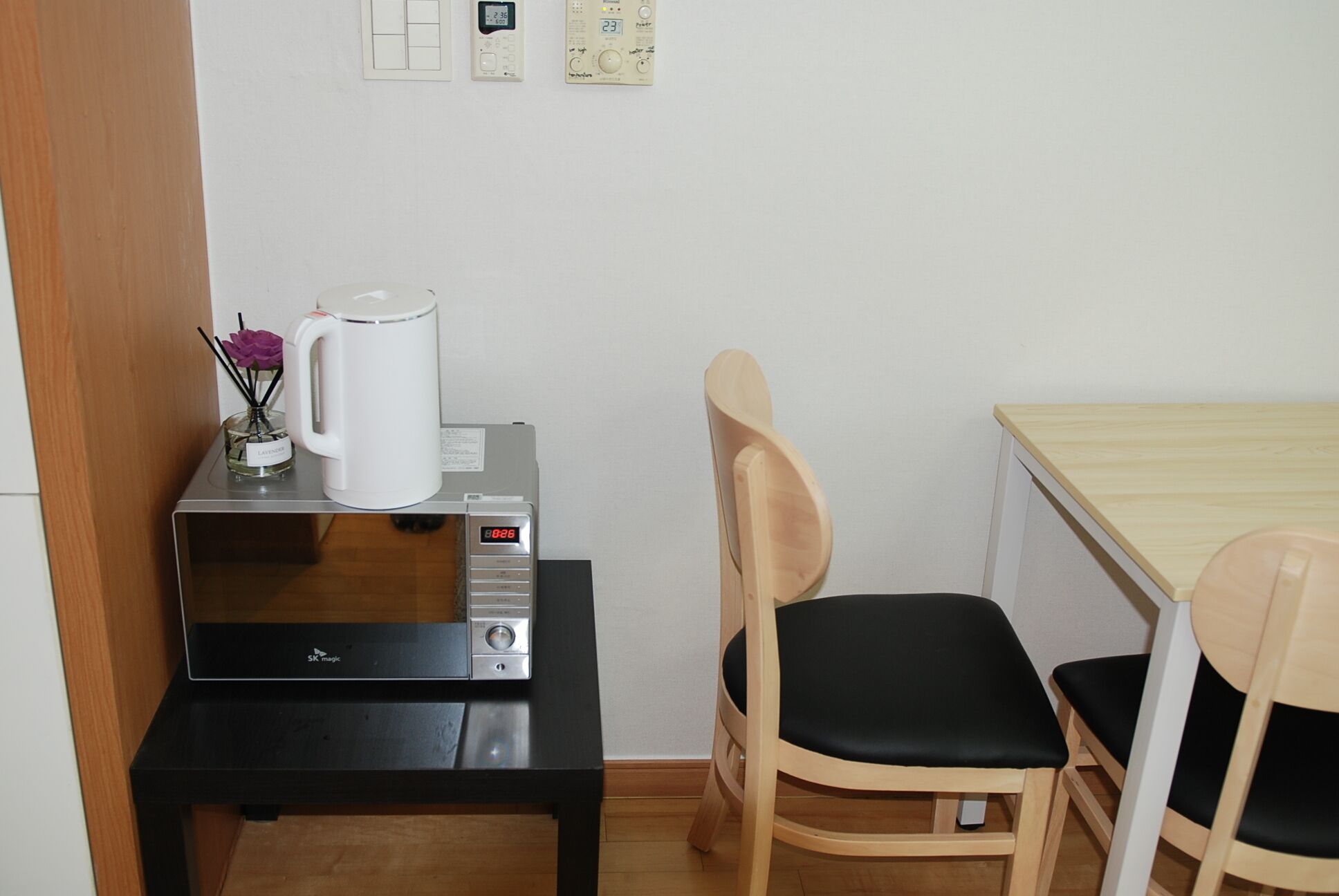 A small kitchenette with a microwave, a coffee maker, and a table with two chairs.
