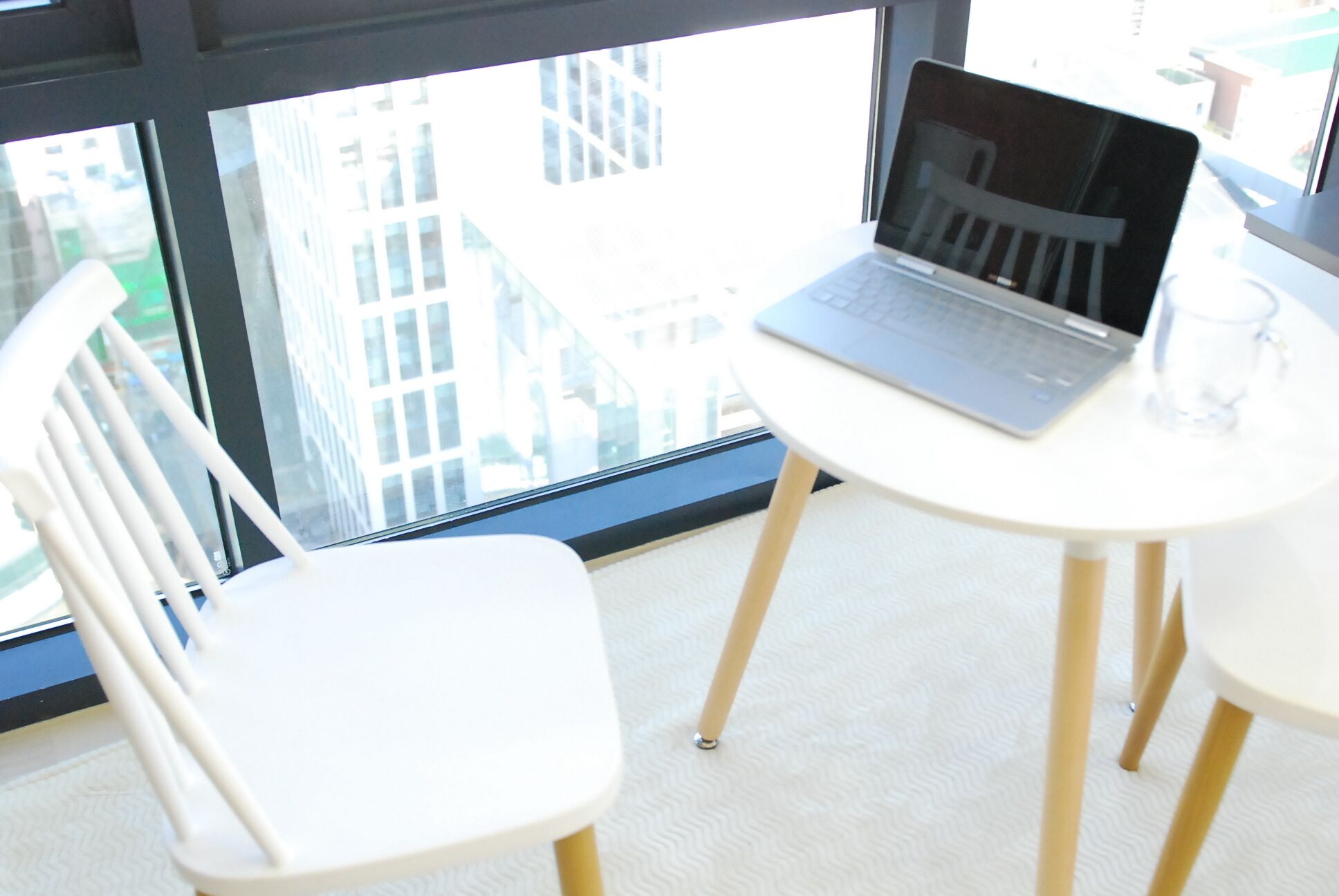 A white chair and a small white table with a laptop.