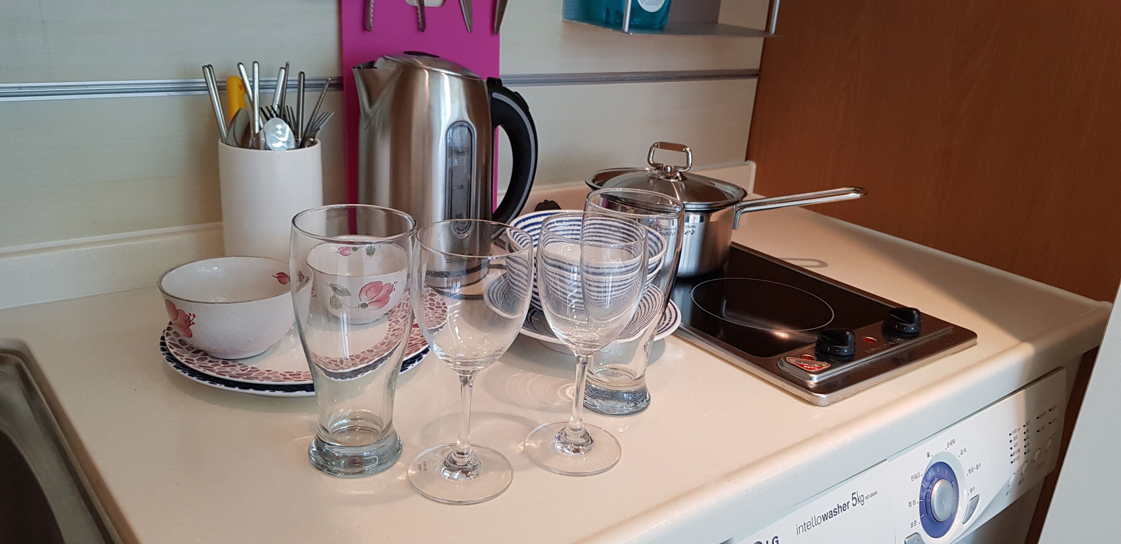 Uma bancada de cozinha com uma chaleira, uma panela e vários copos.