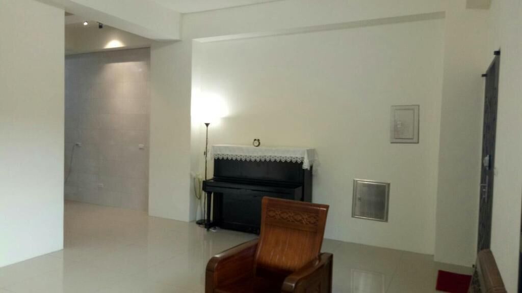A room with a piano, a chair, a door, and a wall-mounted light fixture.