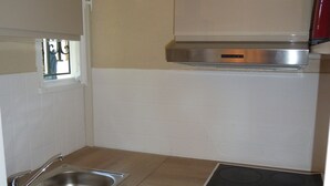 A compact kitchen with a Bosch dishwasher, a stainless steel sink, a stove, and a red microwave. - House with garden, close to the beach, the port and the river shuttle (boucau)