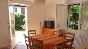 A dining area with a table, chairs, a television, and a view of the outdoors. - House with garden, close to the beach, the port and the river shuttle (boucau)