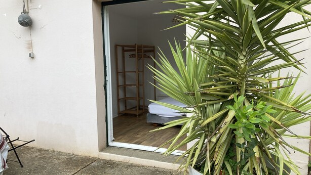 A room with a bed, a wooden chair, and a potted plant. - House with garden, close to the beach, the port and the river shuttle (boucau)