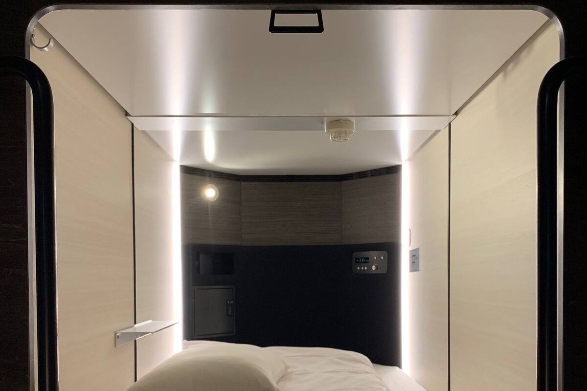 A compact, modern room with a bed, a control panel, and a small control panel with a number 248.