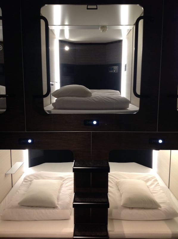 Habitación compacta y moderna con una cama y un espejo sobre ella.