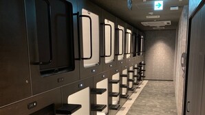 Una hilera de taquillas, un suelo con un estampado, un sistema de ventilación y un cartel direccional en el techo.