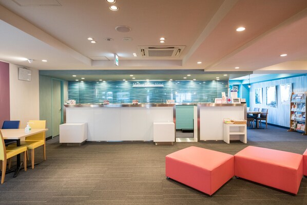 Un moderno vestíbulo de hotel con mostrador de recepción, zona de estar y área de juegos para niños.
