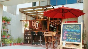 A café with a red umbrella, wooden chairs, and a chalkboard menu. - He-Tian - Cafe & Bar (Puli)