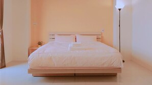 A minimalist bedroom with a bed, bedside table, and lamp. - He-Tian - Cafe & Bar (Puli)