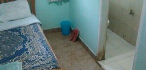 A room with a bed, a blue trash bin, and a pair of red shoes against the wall. - Gitandara Garden Hotel (Othaya)
