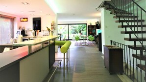 A modern kitchen with a bar area, a staircase, and a large window providing a view of the outdoors. - Schacht34 (Oberhausen)