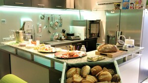 A modern kitchen with a central island, stainless steel appliances, and a variety of food items displayed. - Schacht34 (Oberhausen)