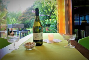 A table with a bottle of wine, two glasses, and a candle, set against a backdrop of greenery. - Schacht34 (Oberhausen)