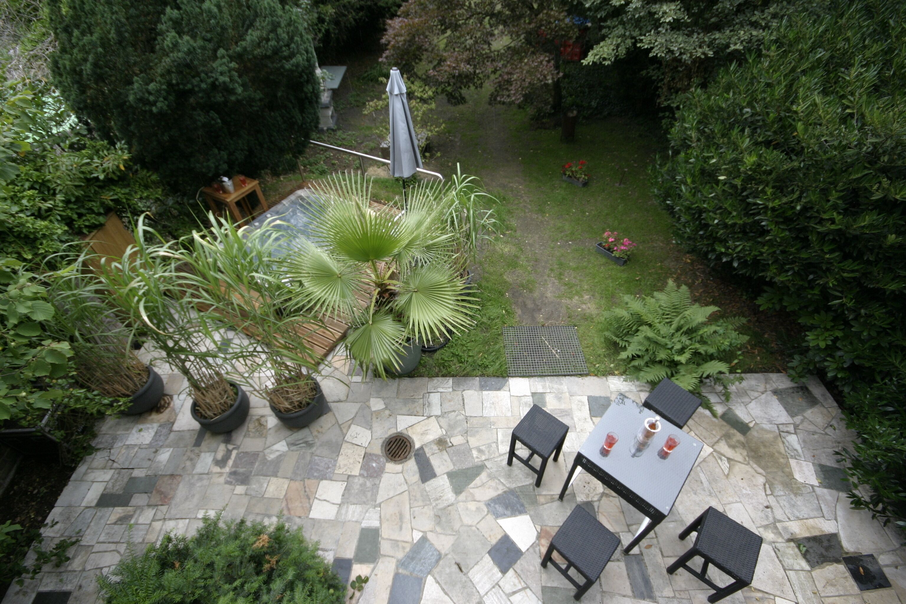 A patio area with stone flooring, a table with chairs, and potted plants.