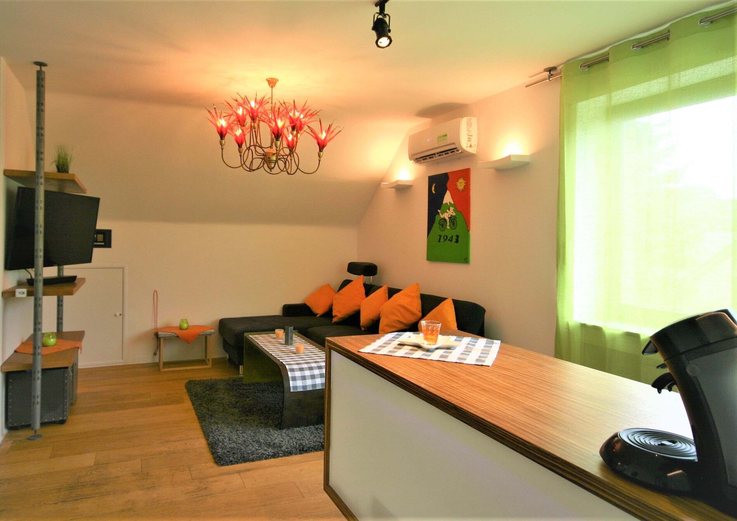A compact living space with a sofa, a small table, a TV, and a chandelier.