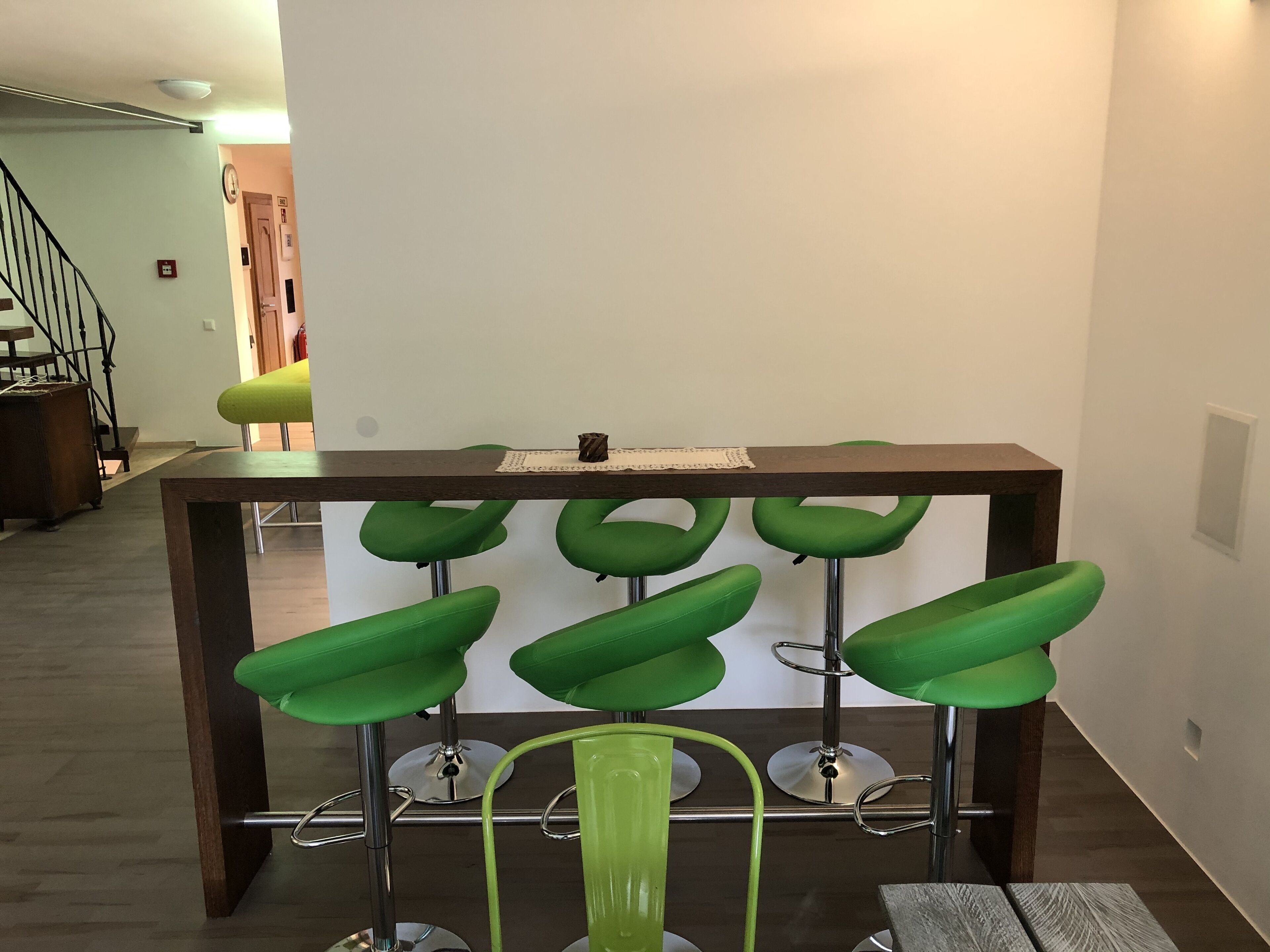 Eine Bar mit sechs grünen Barhocker und einem Holztisch.