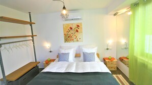 A neatly arranged bedroom with a bed, bedside tables, a hanging light fixture, and a wall-mounted air conditioner. - Schacht34 (Oberhausen)