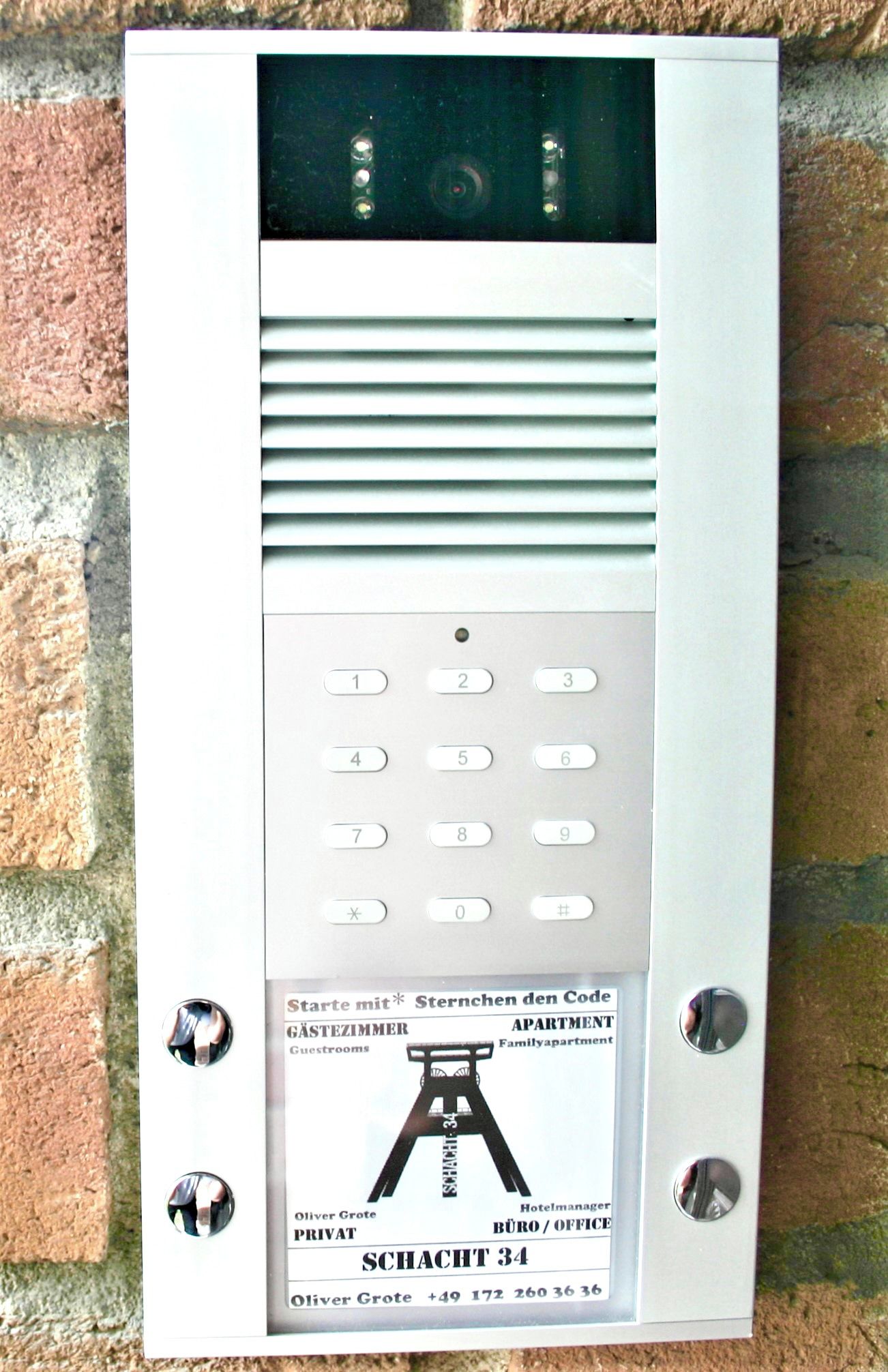 Adgangspanel til et hotelværelse med et tastatur, et digitalt display og et skilt, der angiver rumnummer og faciliteter.