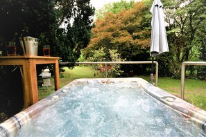 A hot tub in a garden with a wooden table and metal chairs. - Schacht34 (Oberhausen)