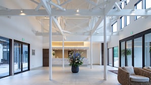Un hall d’entrée spacieux, doté d’un haut plafond, de grandes fenêtres et d’un arrangement floral central.