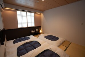 A room with two beds, a window, a bedside table, and a wall-mounted air conditioner. - Soar Resort (Tsushima)