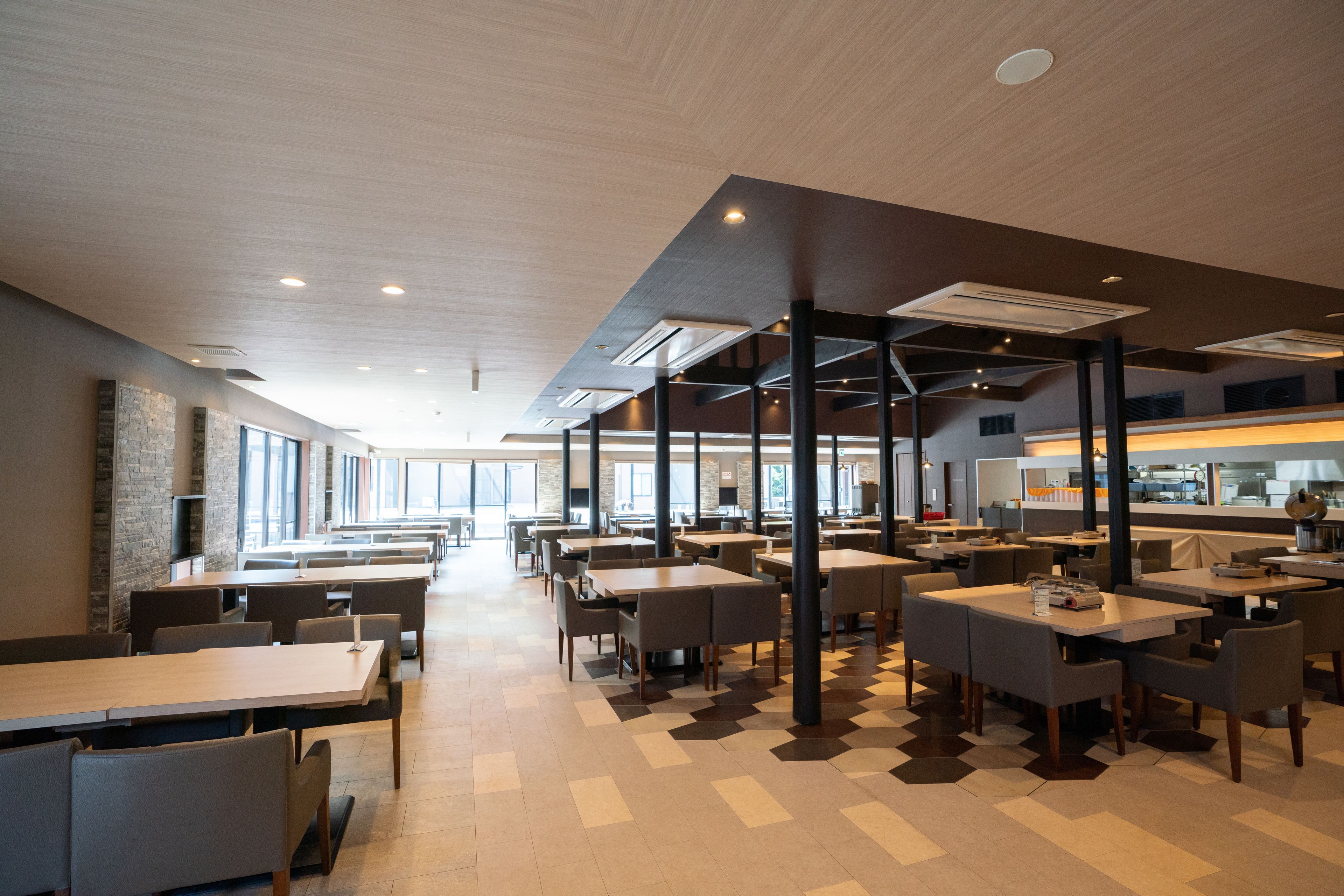 A modern dining area with high ceilings, large windows, and a checkered floor pattern.