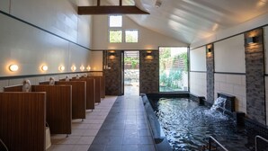 Un espace spa avec des cloisons en bois, un jacuzzi et une vue sur la verdure environnante.