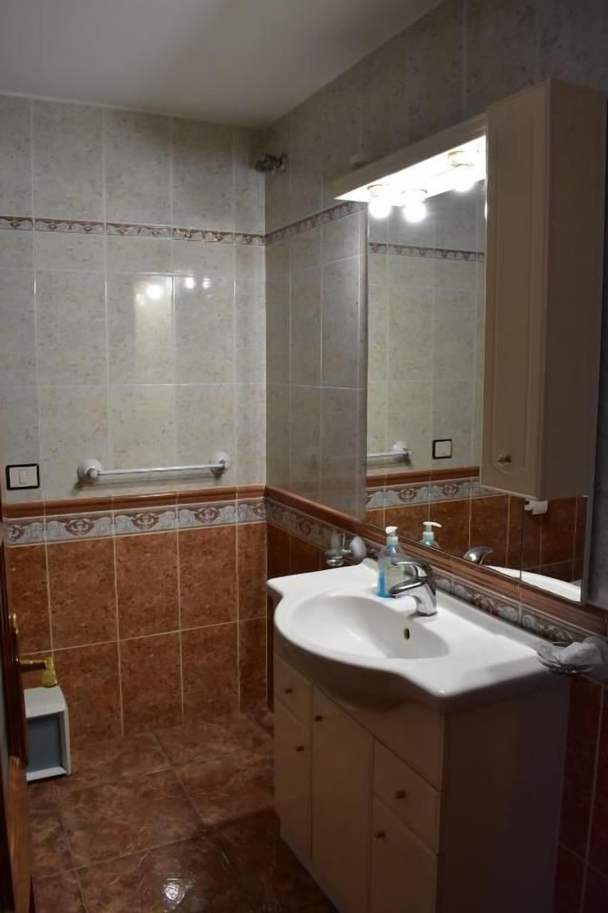 Ein Badezimmer mit Waschbecken, Spiegel und Fliesen.