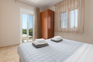 A bedroom with a bed, a wardrobe, and a view through a window.